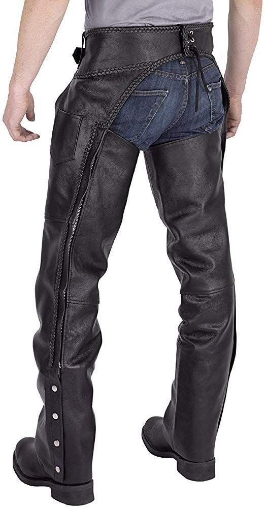 full shot image showing a man wearing a pair of black leather chaps over a pair of blue jeans. the chaps are fastened with a laced waist belt and have zippers running down the sides. the chaps extend to the ankles, covering the man's boots. the man is standing with his legs slightly apart.