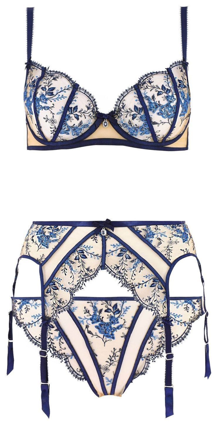 an image shows a white lingerie set with blue floral embroidery. the set includes a bra and a garter belt. the bra has underwire cups, adjustable straps, and a floral design with blue detailing. the garter belt features similar floral patterns, blue trim, and adjustable straps.