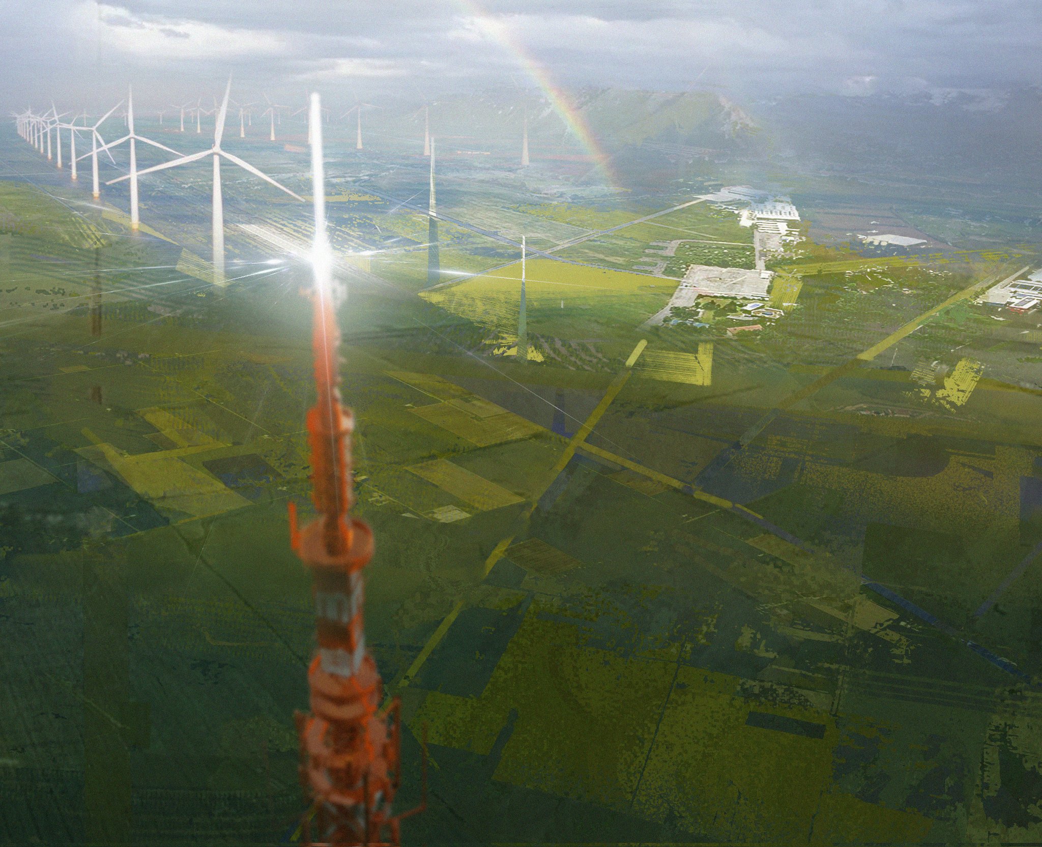 this is an aerial view of a wind farm in a rural area. there are many wind turbines, a rainbow, a road, and a few buildings.