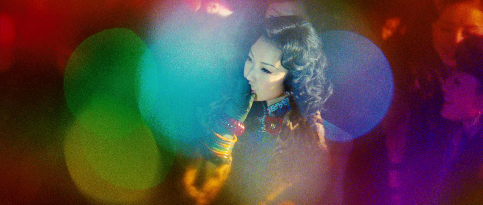 a woman with dark hair dances in a nightclub. the image is blurred and uses a colorful bokeh effect.