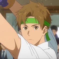 this is a close up illustration of an anime boy with brown hair and brown eyes. he has a green headband on and is wearing a white shirt. it looks like he's in motion, with his arm raised and holding something, but that portion of the image is cut off.  the background suggests he's indoors, perhaps at a school.