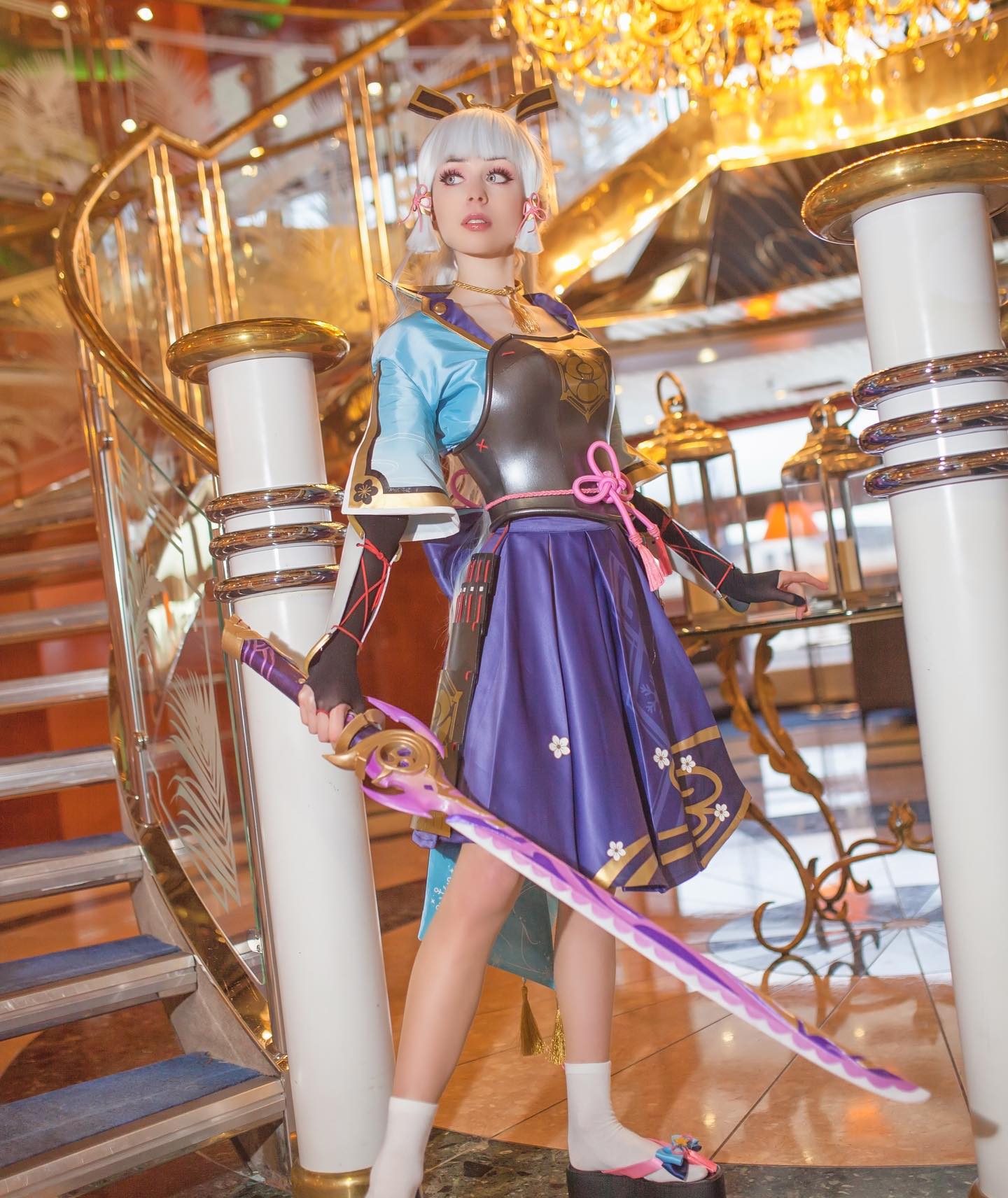 a meticulously crafted cosplay of genshin impact's kamisato ayaka is showcased in this image. the cosplayer, a young woman, is dressed in a stunning recreation of ayaka's signature attire: a purple and white kimonoinspired dress, silver armor breastplate, and decorative hair ornaments. she holds a large, vibrant purple and gold sword, a key prop from the game. the setting is a grand, opulent interior featuring a curved staircase with gold accents and elegant furnishings, contributing to an upscale atmosphere and complementing the costume's detailed design.  the photograph highlights both the costume's quality and the cosplayer's resemblance to the character.