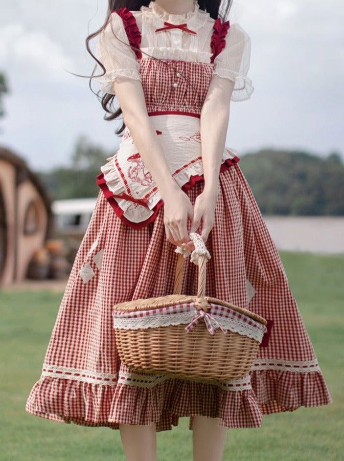 a young woman in a red and white checkered lolita fashion dress stands in a field. she is holding a picnic basket and is facing forward. the dress has a ruffled hem and a white laceup top. the photo is taken from an eyelevel perspective and the lighting is natural and sunny.  the overall feel is romantic and whimsical.