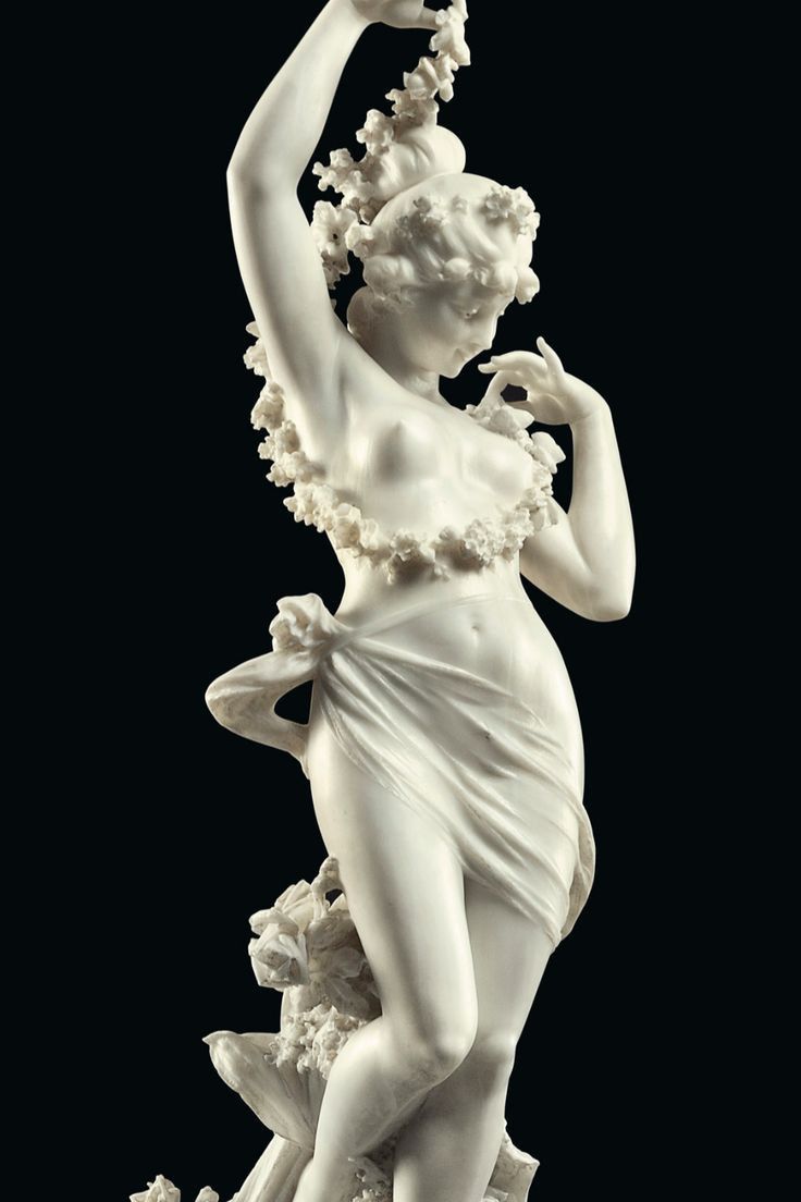 this is a closeup view of a white marble sculpture of a nude woman. the woman's body is beautifully sculpted, and she is draped in a flowing fabric that seems to be made of flowers. her pose is graceful, and her expression is serene. the sculpture is a work of art that is both beautiful and timeless. it is a testament to the skill and artistry of the sculptor.