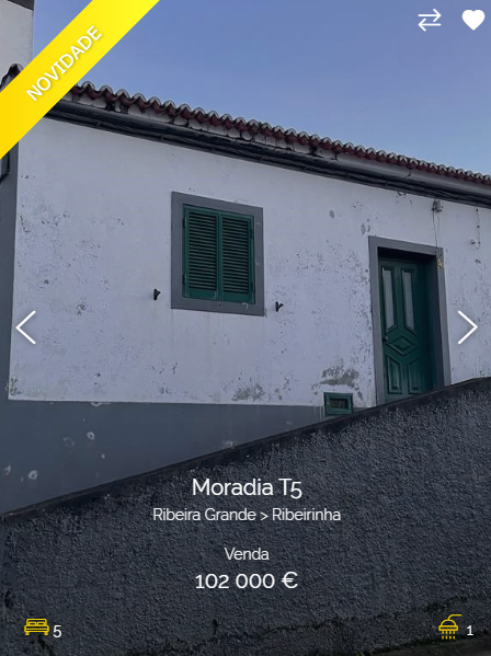 a white house with a green door and window for sale in portugal. the house has a sloped driveway and is in the suburbs.  the house has a sign that says "moradía t5, ribeira grande > ribeiirinha, venda 102 000 €."