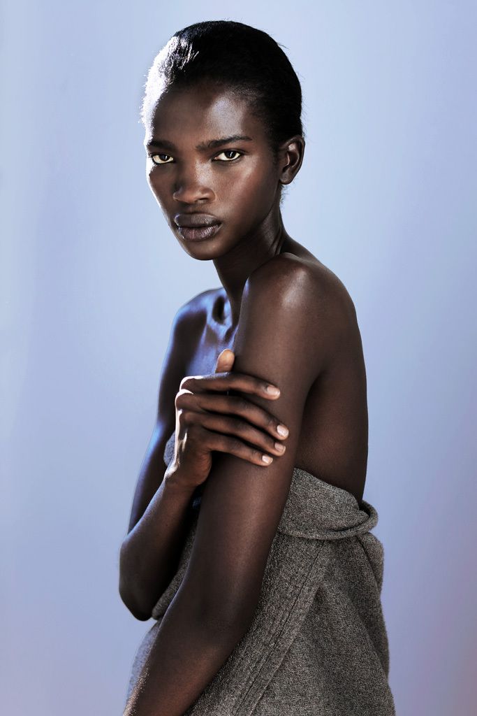 a closeup portrait of a beautiful black woman posing in a studio. she is wearing a gray towel wrapped around her
