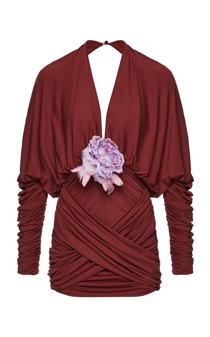a maroon longsleeve dress is displayed on a white background. the dress features a vneck design, ruched detailing around the waist, and a flower embellishment on the front.