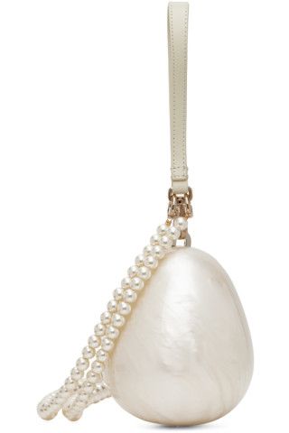the image shows a closeup of an ivorycolored handbag in the shape of a teardrop or egg. it has a pearl chain detail and a short, leatherlike strap attached at the top with goldtoned hardware. the bag has a smooth, textured surface.
