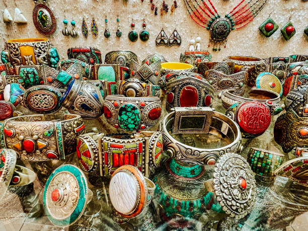 the image showcases a vibrant and intricate display of handmade jewelry, including bracelets, rings, necklaces, and earrings. the pieces are adorned with various gemstones such as turquoise and coral, set in silver and gold. the collection appears to be from a market, shop, or store specializing in ethnic and traditional artisan jewelry.