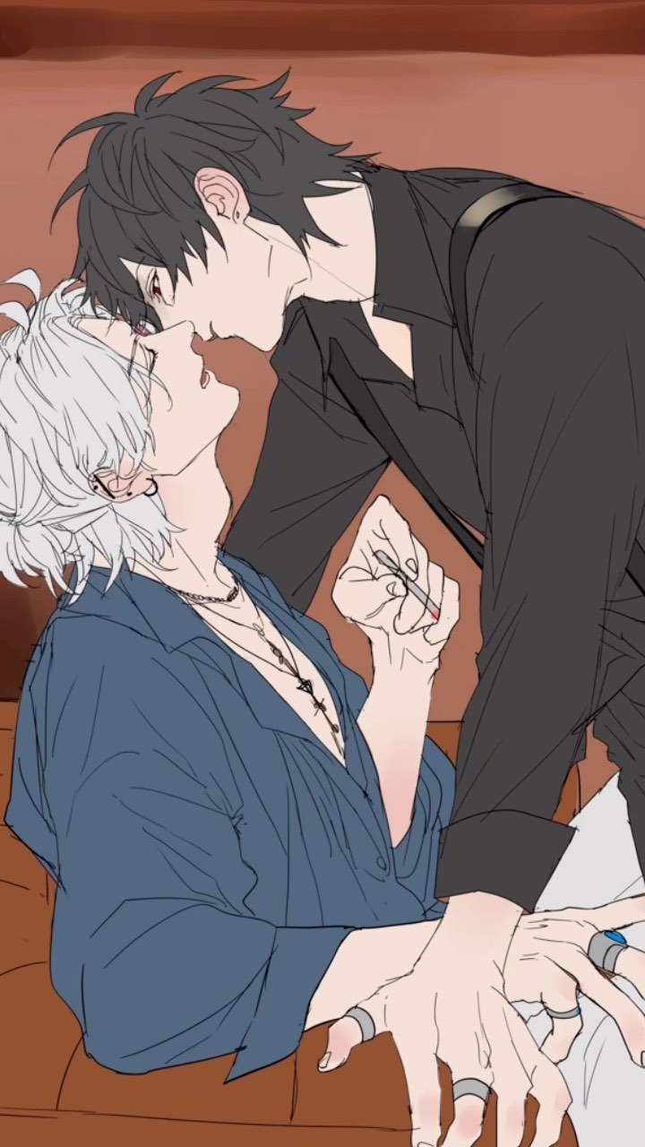 the image is a drawing or illustration in an anime or manga style. it depicts two young men, one with dark hair and one with white hair, in a romantic embrace. they are sitting close together on a couch, their faces close as if about to kiss. the man with dark hair is leaning over the other, and their hands are intertwined. both men are wearing jewelry, including rings. the man with dark hair is dressed in darker clothing, while the man with white hair wears a light blue shirt. the style is suggestive of boy's love (bl) or yaoi, a genre of manga and anime focusing on romantic relationships between men.