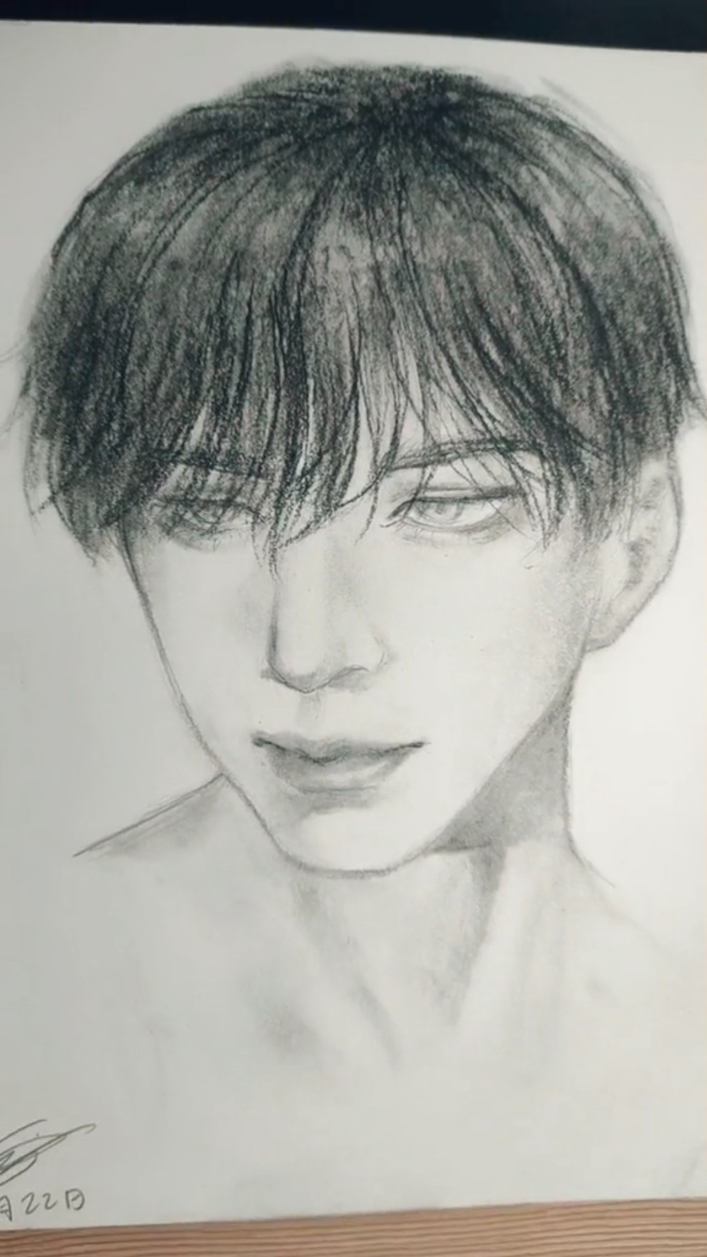 a wellexecuted charcoal sketch of a young man's face and shoulders. the portrait is done in a realistic style, capturing the subtle nuances of light and shadow. the man's expression is neutral, with a hint of a smile.  the focus is on the subject's features, set against a plain, undefined background.