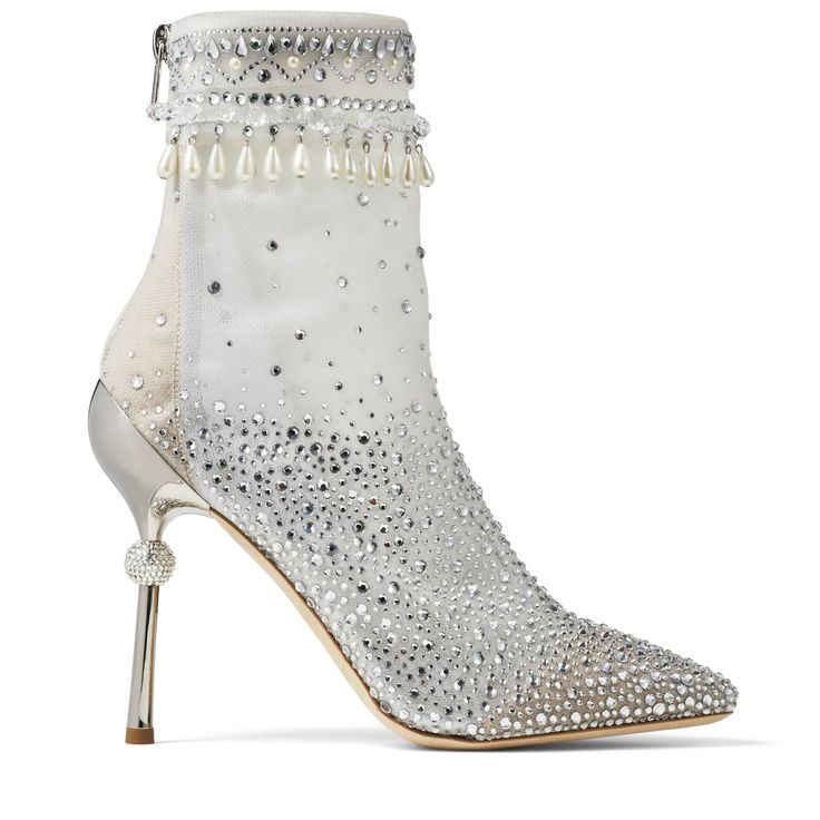 a silver and white stiletto heel ankle boot with crystals, pearls, and beading on a white background. the boot has a silver heel and a silver covered heel with a small bead detail on the back of the heel. the top of the boot is white with a band of pearls, beading and crystals, and a string of dangling faux pearls. the boot fades from crystals at the toe to a semi transparent netting on the upper boot.