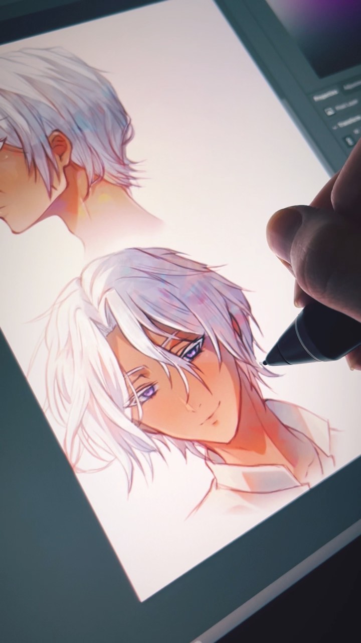 a closeup shot of a hand using a stylus on a graphic tablet to create digital art. the artwork depicts two variations of a young animestyle male character with white hair and purple eyes. the character is drawn in a soft, light style, with warm skin tones. the artist's hand is partially visible, holding the stylus. the graphic tablet is illuminated, showing the progress of the artwork. the overall mood is peaceful and focused.