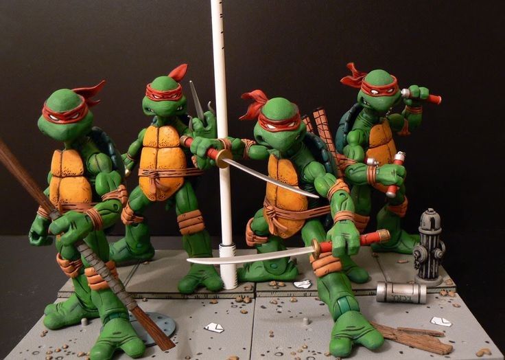 the image shows four teenage mutant ninja turtles action figures posing on a street diorama. each turtle is wearing a red bandana and holding their respective weapon: a bo staff, two sai, two katanas, and two nunchucks. a sewer cover, a fire hydrant, and debris are scattered around the street.