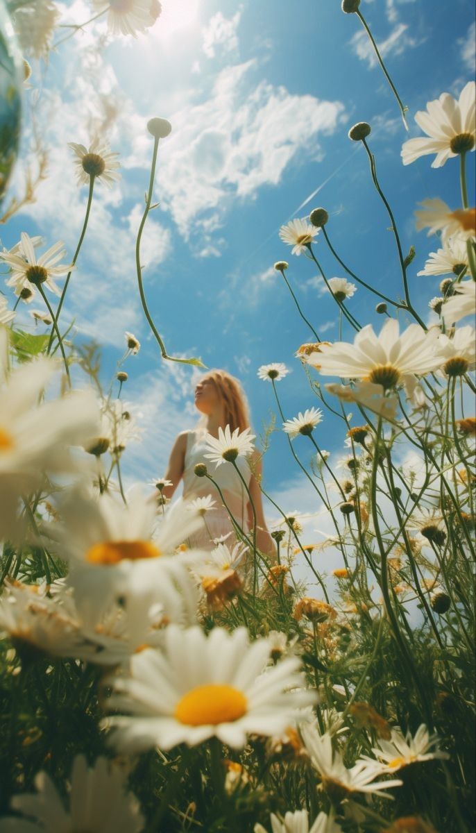 a lowangle shot of a young blonde woman standing in a vibrant field of daisies, looking up at the bright sunny sky. the flowers surround her, creating a beautiful and peaceful scene. the overall feeling of the image is one of happiness and serenity.