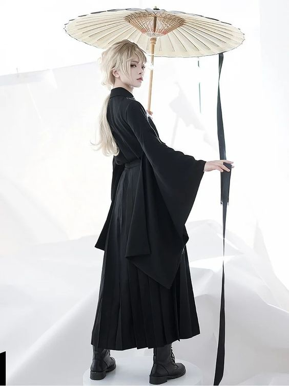a person with long white hair, styled in a bob, is posing in a black kimonoinspired dress. they are holding a traditional japanese umbrella with a black and white design.  the background is entirely white, creating a stark contrast and emphasizing the model and their attire. the lighting is soft and diffused, resulting in minimal shadows.