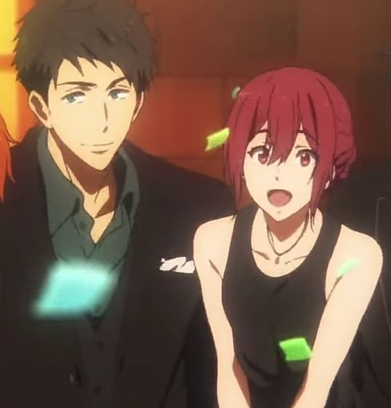 an anime couple smiling happily in front of a warm, orange background, with green and blue confetti falling around them.  the man, on the left, is wearing a black suit jacket over a dark teal shirt.  the woman is wearing a black tank top and has a silver necklace.