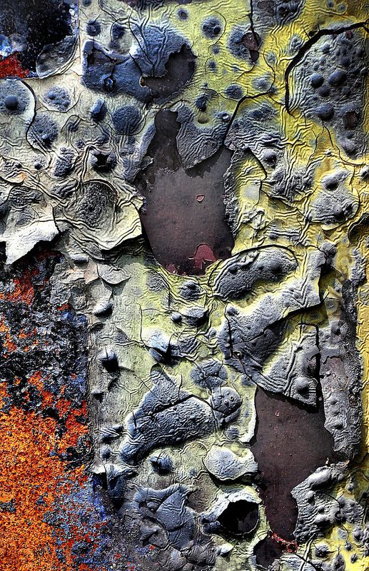 a closeup shot of a weathered metal surface with peeling paint. the paint is chipped and cracked, revealing the rusty metal underneath. the colors are a mix of yellow, gray, and brown, creating a textured and abstract pattern. the image has a grunge aesthetic and could be used as a background for a variety of projects.