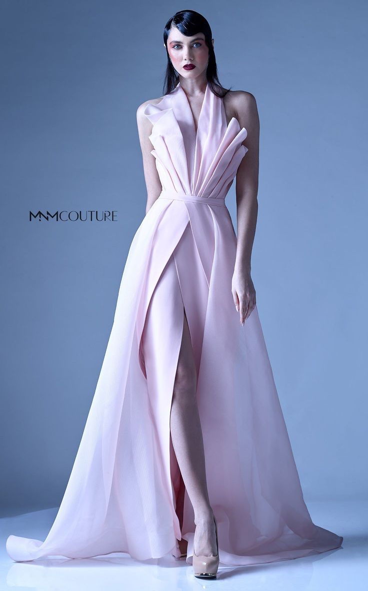 a beautiful woman in a pink gown with a high slit posing on a studio background. her hair is swept back and she is wearing high heels. the dress is elegant and flowing, and the model is looking confident and stylish.