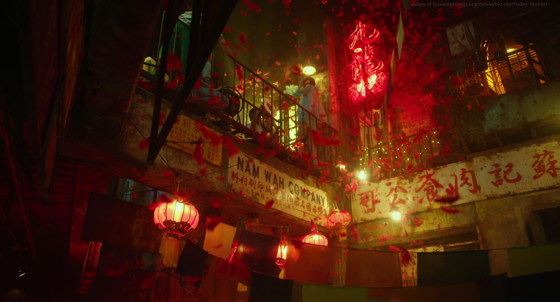 a bustling night scene in a chinese city, with red lanterns hanging from a building. the street is crowded with people celebrating and the air is filled with red feathers. there is a sign that says "nam wah company." the atmosphere is festive and joyous.