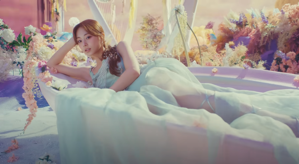 a young woman is posed languidly in a bathtub overflowing with pastelcolored flowers. she is wearing a flowing, semisheer gown in shades of pale blue and purple, and her hair falls in loose waves around her shoulders. the overall aesthetic is soft, feminine, and dreamlike, with a pastel color palette and diffused lighting.