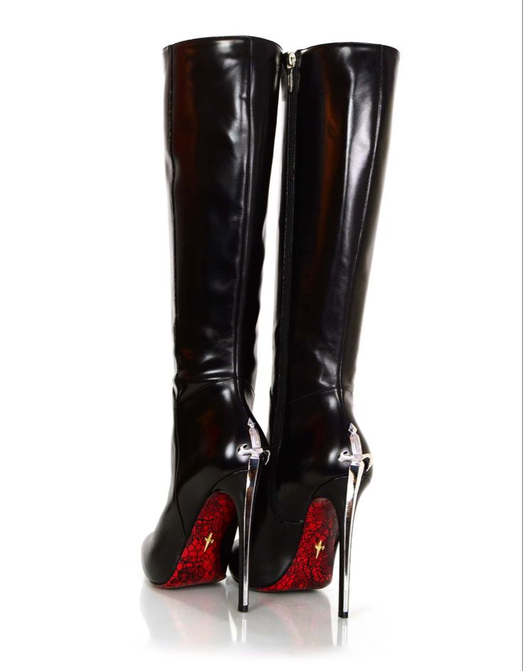 a pair of black leather kneehigh boots with stiletto heels and red soles are shown from the back. the boots feature silver dagger accents on the heels.  they are positioned on a white background. the image highlights the boots' details and design.