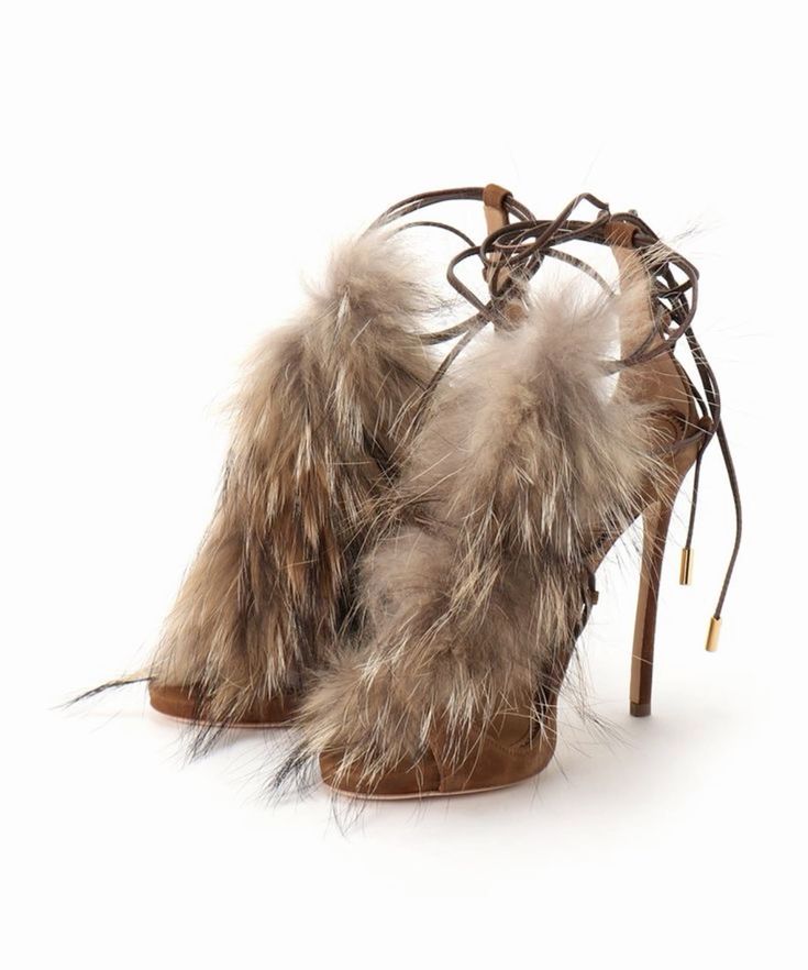 a pair of brown suede high heels with fur trim. the heels are laceup and have ankle straps. they are very stylish and glamorous.