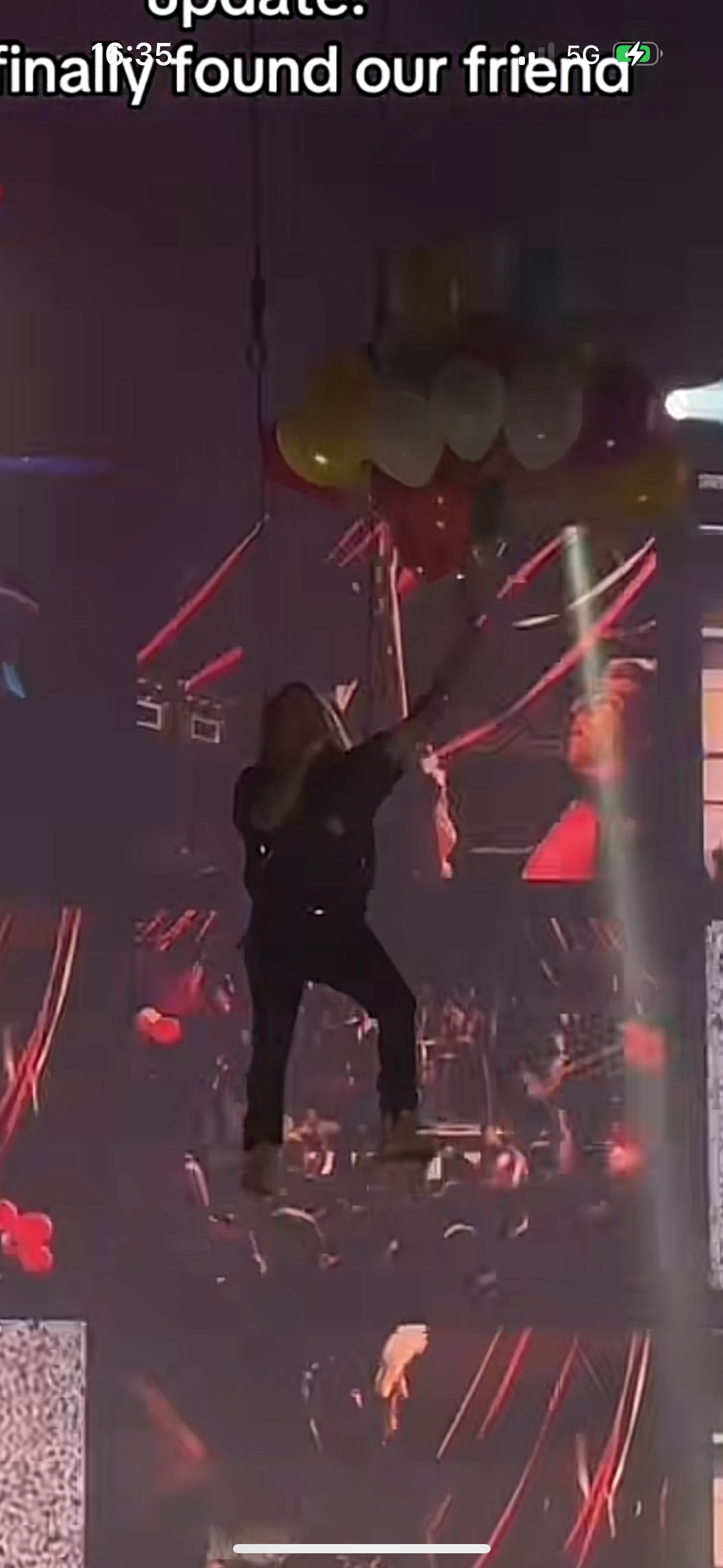 a concert crowd cheering as a musician performs on stage. the crowd is illuminated by bright stage lights, and the performer is singing into a microphone.  the image is shot from a closeup perspective, making the energy and excitement of the concert palpable.