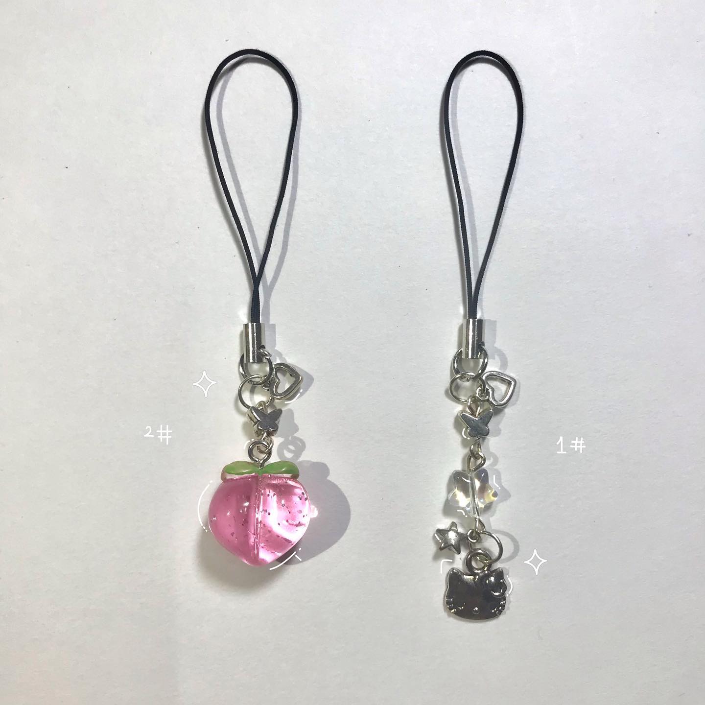the image contains two phone charms or keychains. one is a pink peach shape, and the other is a hello kitty character.