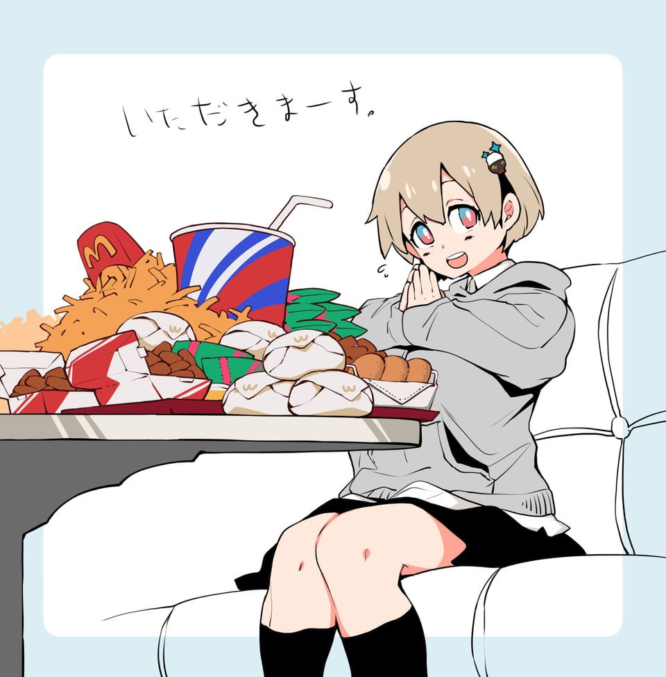 a cartoon anime girl with short blonde hair is smiling and sitting in a white couch. she is wearing a gray sweater, black skirt, and black stockings. she is looking at a table full of fast food, including fries, chicken nuggets, and a large soda. the table is in front of her and she is wearing a happy and excited expression. she looks like she is enjoying her meal. the text on the top left says "itadakimasu".