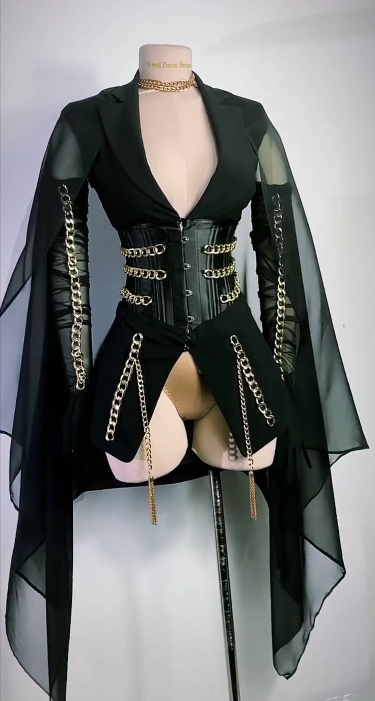 a black and gold outfit with a blazer, corset, chains, and a cape, perfect for a party or a night out. it is displayed on a mannequin.