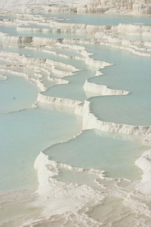 the image showcases the stunning travertine terraces of pamukkale in turkey. the landscape is dominated by bright white terraces formed by mineralrich thermal waters, creating a mesmerizing natural wonder. pools of turquoise water collect in the terraces, adding a vibrant contrast to the white backdrop. the geological formation of calcium carbonate deposits is evident, making it a unique and popular tourist destination.