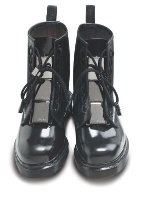 the image shows a pair of black, highgloss leather ankle boots.  the boots are laceup style and feature distinctive rectangular silver metallic inserts on each boot, creating a unique design element. they appear to have a slight platform or chunky sole. the boots are positioned centrally against a white background, showcasing their details clearly. the style is fashionable and contemporary.