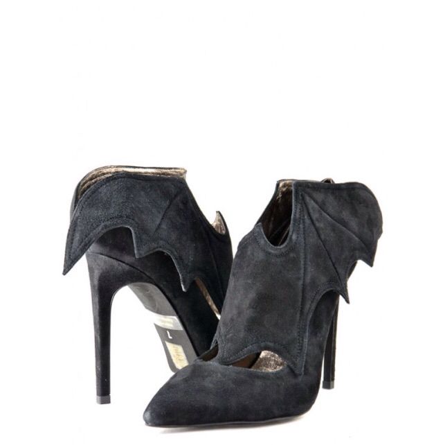 two black suede high heels with bat wing design elements are positioned against a white background. the shoes have a pointed toe and a stiletto heel.