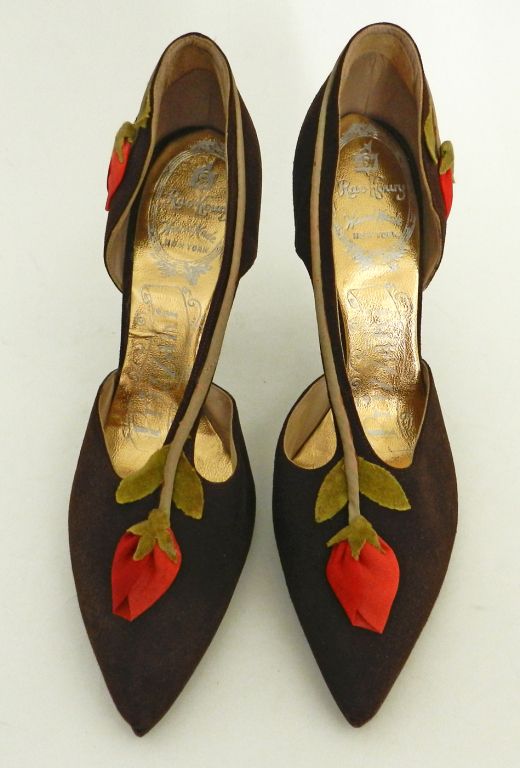 two highheeled shoes are shown in the image. they are brown with red flower accents. the inside of the shoes are gold.