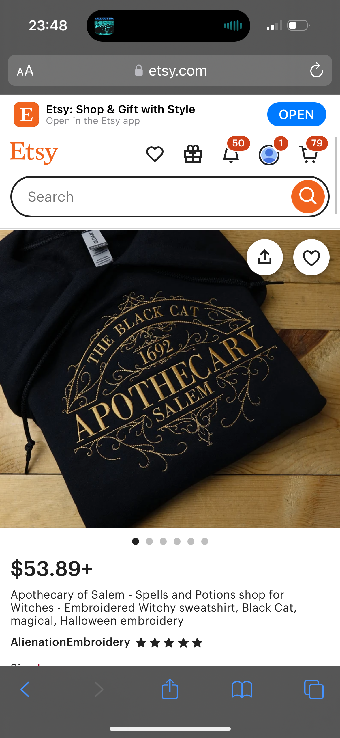 this is a product listing on the etsy website for a black sweatshirt with a gold embroidered design that reads "the black cat 1692 apothecary salem." the design has a vintage aesthetic, perfect for halloween. the sweatshirt is listed as "witchy" and is sold by the shop alienationembroidery. the product is available for $53.89. the image shows the sweatshirt laid out flat on a wooden surface with the text "the black cat 1692 apothecary salem" visible in the center of the design.