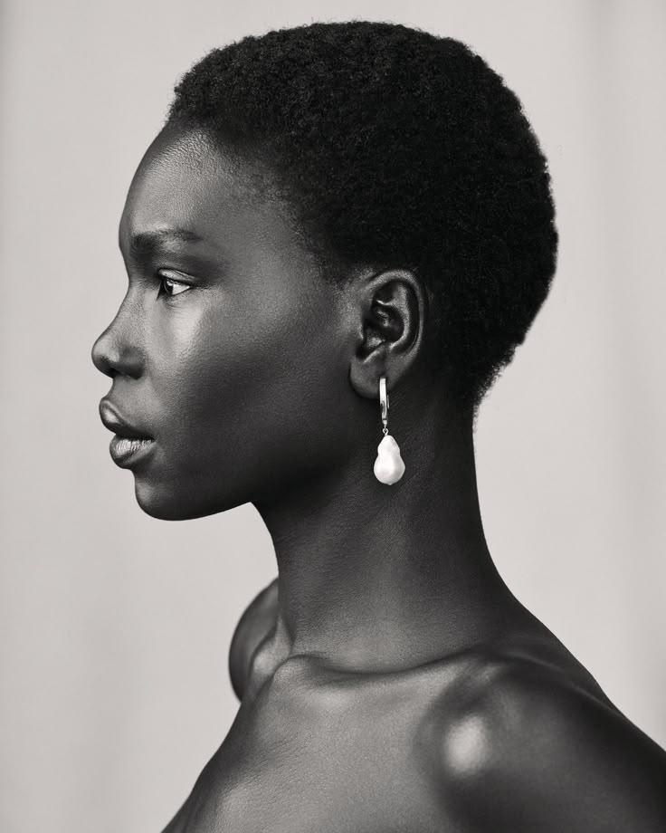 a black and white portrait of a woman with dark skin, short hair, and a pearl earring, shown in profile.