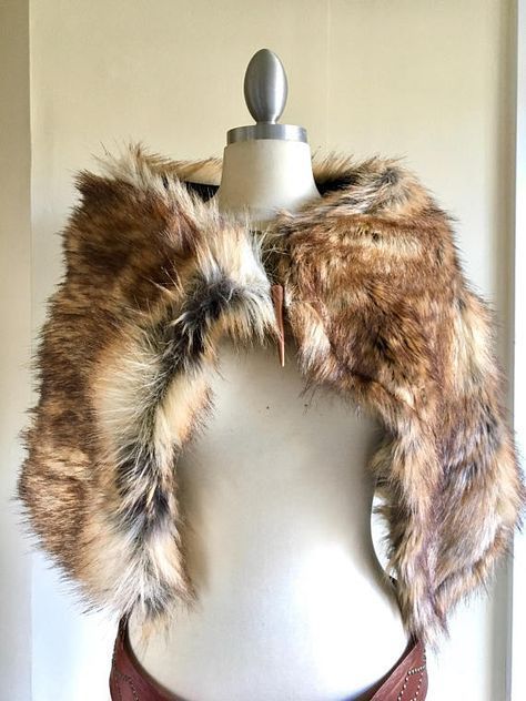a brown faux fur collar is displayed on a mannequin. the collar is voluminous and has a mix of brown, tan, and black colors. a leather belt with studs is seen at the base of the mannequin.