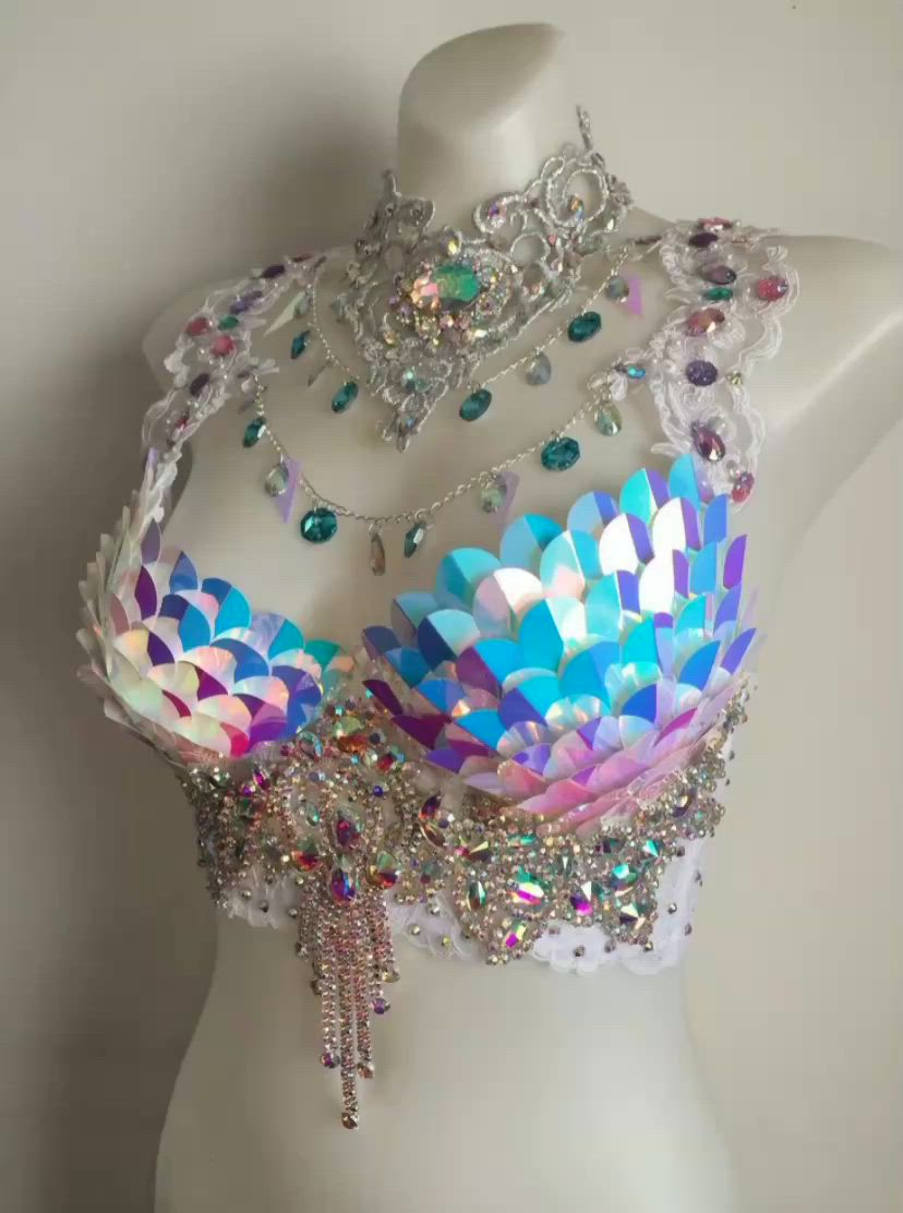 a rhinestone bra and a necklace are displayed on a white mannequin. the bra is adorned with iridescent sequins and silver embellishments. the necklace is a lace choker.