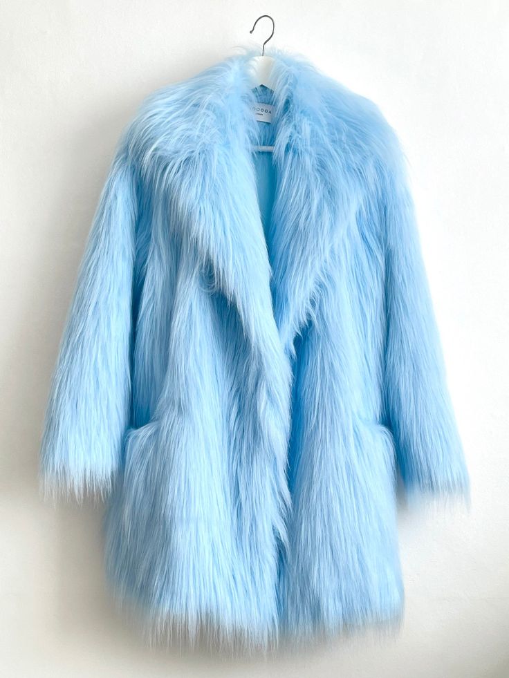 a light blue faux fur jacket hangs on a white hanger against a white background. the jacket is fluffy and soft, with a long, fuzzy collar. it is a classic winter coat style that is sure to keep you warm and stylish.