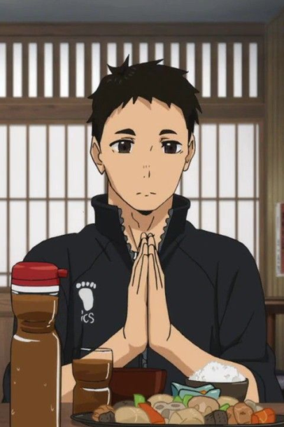 an anime man sitting with his hands clasped in prayer in front of a plate of japanese food.  he is wearing a black athletic jacket with white zipper and trim.  the background is pale yellow wood slats.