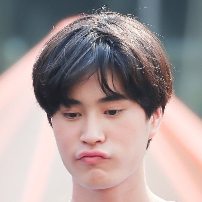 a portrait of a young asian man with short black hair. he has a slightly pouty expression and is looking down.