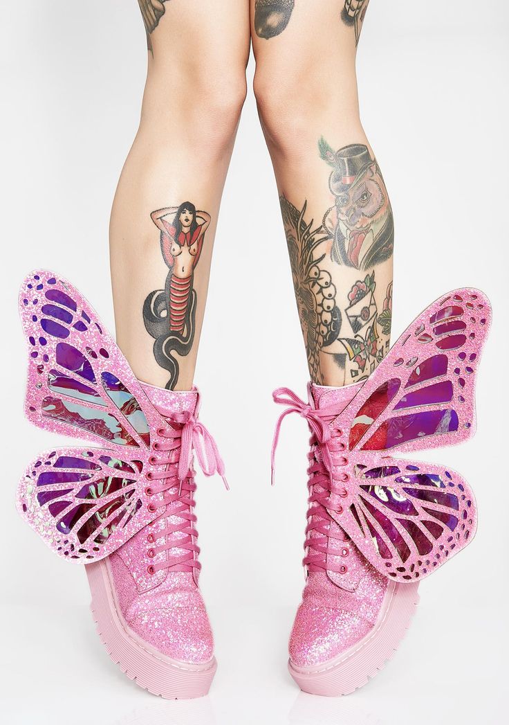 a pair of legs with tattoos wearing pink glitter boots with butterfly wings.