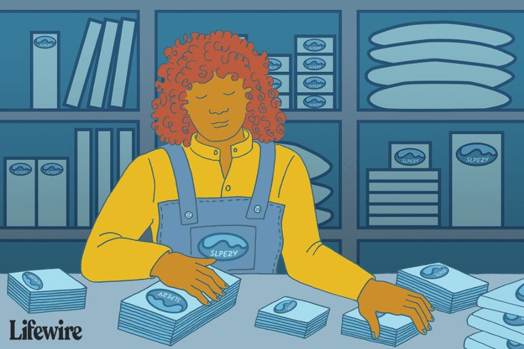the image is an illustration of a woman standing behind a table with stacks of packages on it. the packages are labeled "slpezy". behind the woman is a set of shelves stocked with more packages of various sizes, along with a few books. the woman has curly red hair and is wearing a yellow shirt and blue overalls. the "lifewire" logo is in the lower left corner.