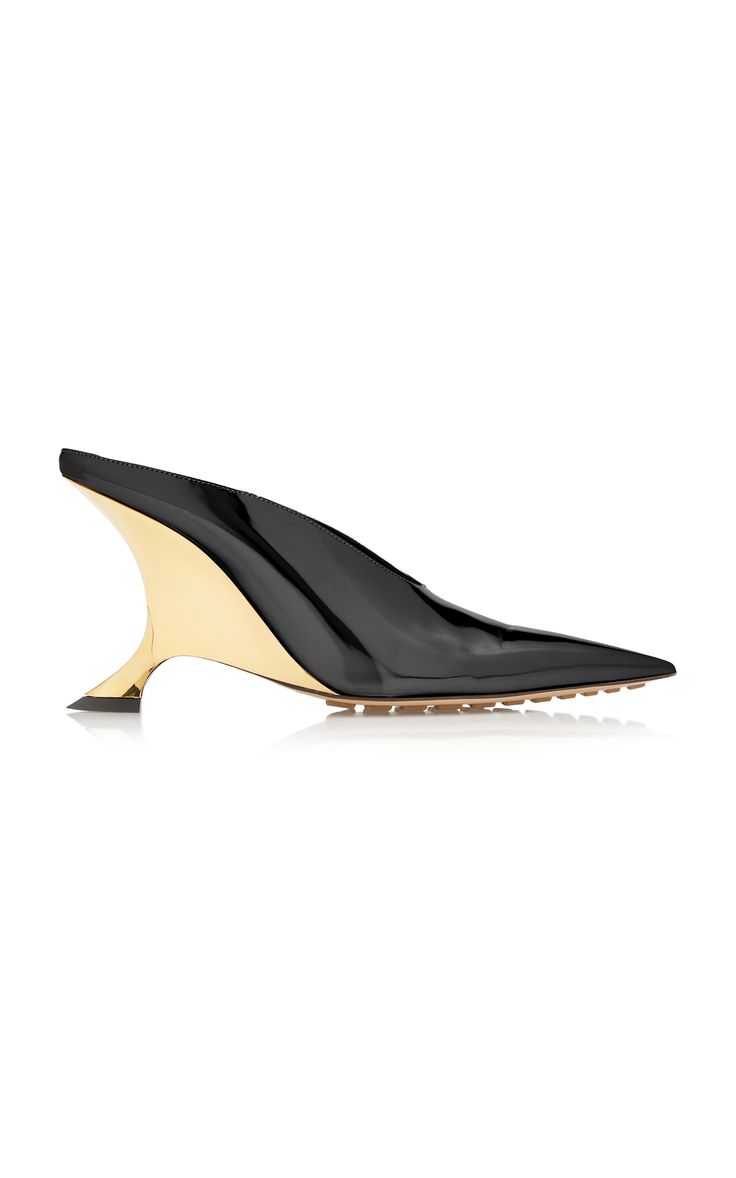 the image shows a pair of women's black patent leather mules with a unique gold sculptural heel and a pointed toe.  the shoes are positioned on a white background, and their reflection is visible below. the style is modern and elegant.