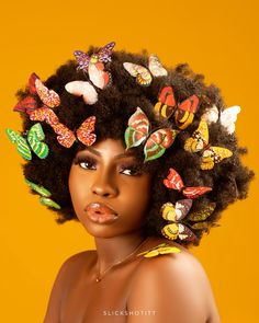 a portrait of a woman with a large afro adorned with colorful butterfly decorations set against a vibrant yellow background. she has flawless makeup and a captivating gaze.