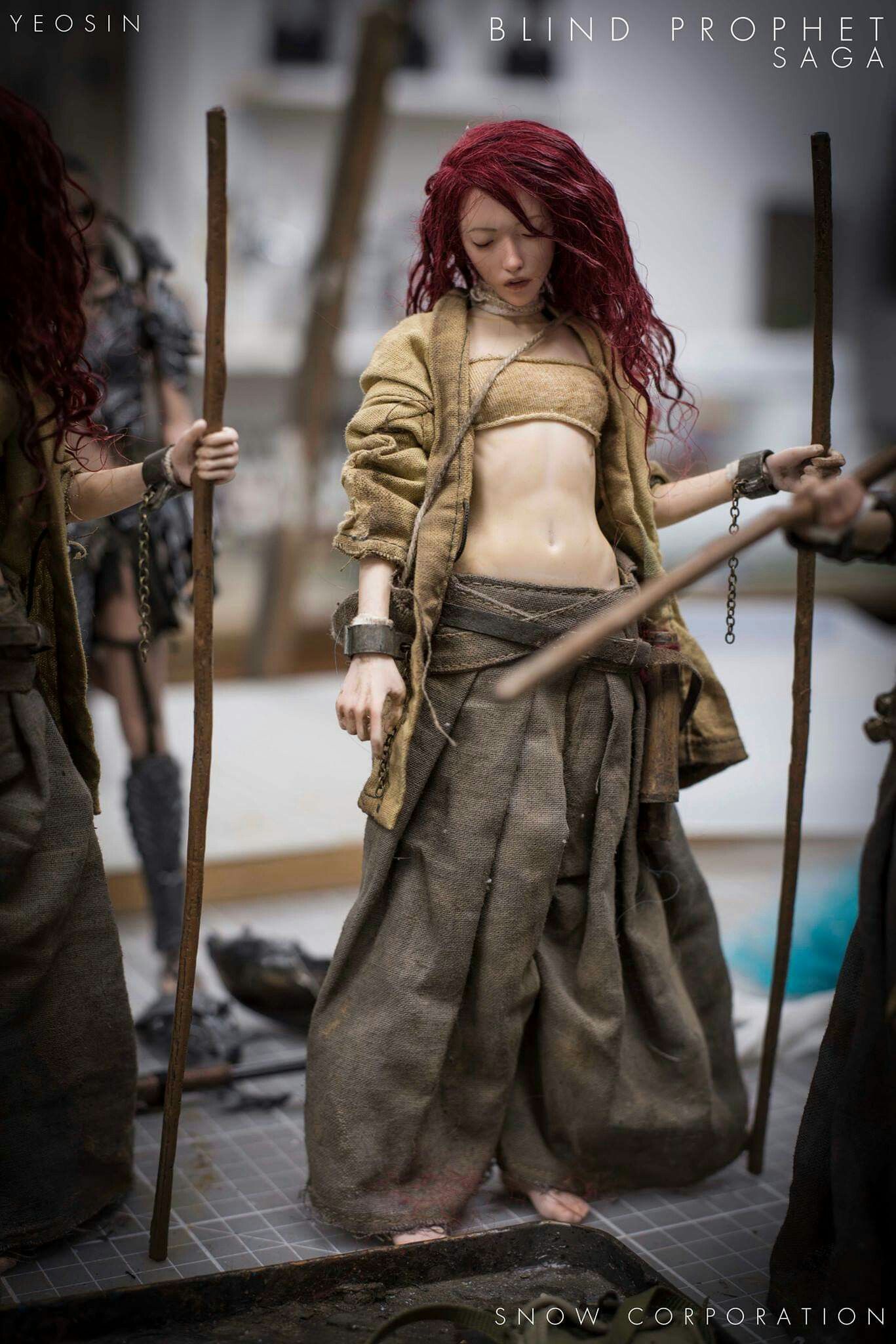 a close up image of a female action figure from the "blind prophet saga". the figure is standing and dressed in brown clothing. she has red hair, a leather strap around her waist, and is holding a sword. the background is out of focus and the figure is the main focus of the image. the figure is barefoot. the image is taken in a studio setting with studio lighting.