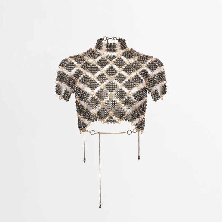 a beaded top with chainmail design and gold chains hanging from the bottom.