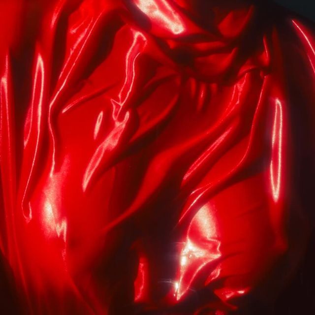a closeup shot of a vibrant red satin fabric with dramatic folds and wrinkles. the fabric is smooth, shiny, and luxurious, creating an abstract background with captivating textures. the deep red color and the way the fabric drapes creates a sensual and luxurious feel.  the smooth surface and the deep color create a rich and elegant look. the image is perfect for illustrating concepts like beauty, luxury, and passion.