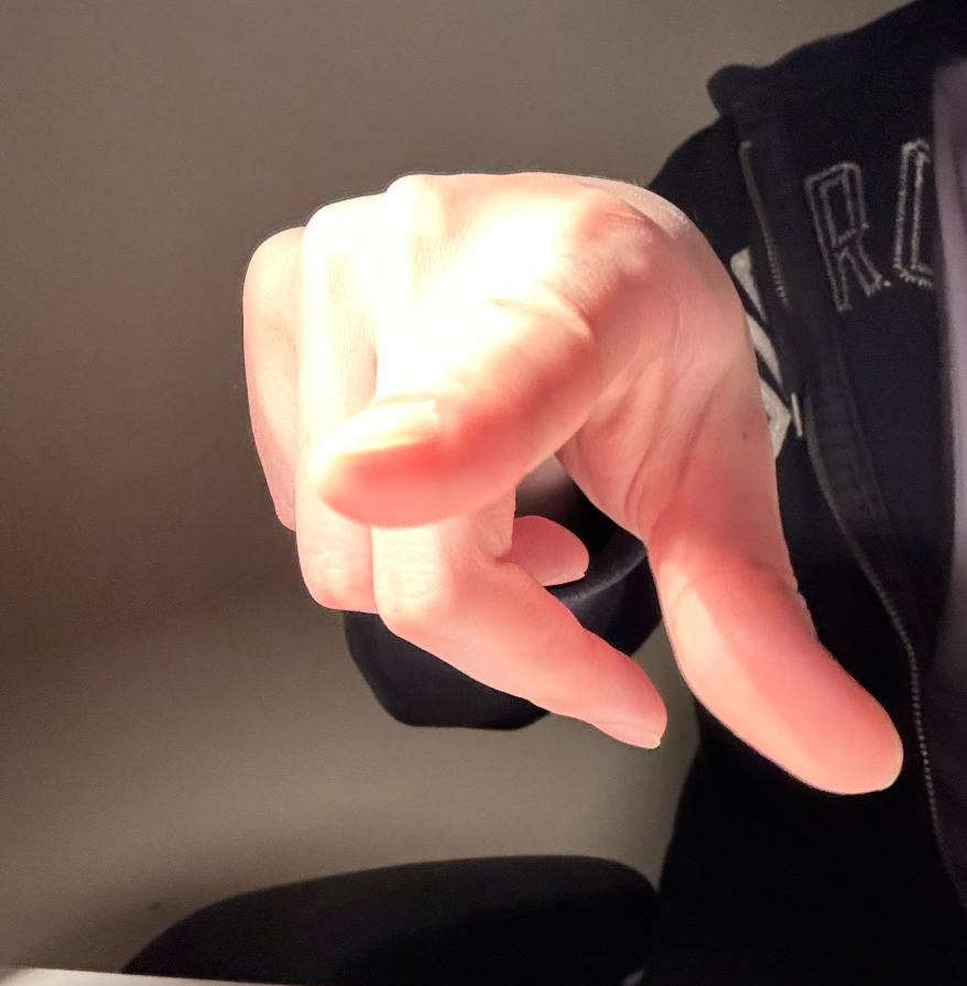 a person's hand is outstretched with their index finger pointed, as if gesturing towards something. the hand is illuminated by a warm, artificial light source. the background is blurred, suggesting an indoor setting. the image is taken from a firstperson perspective.